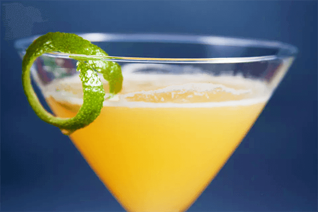 Drink Cocktail Flirtini com casca de limão na borda da taça.