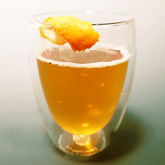 Copo de drink com gin e casca de laranja na borda.