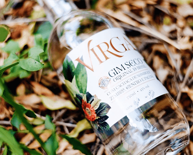 Garrafa do gin Virga sobre folhas marrons e verdes.