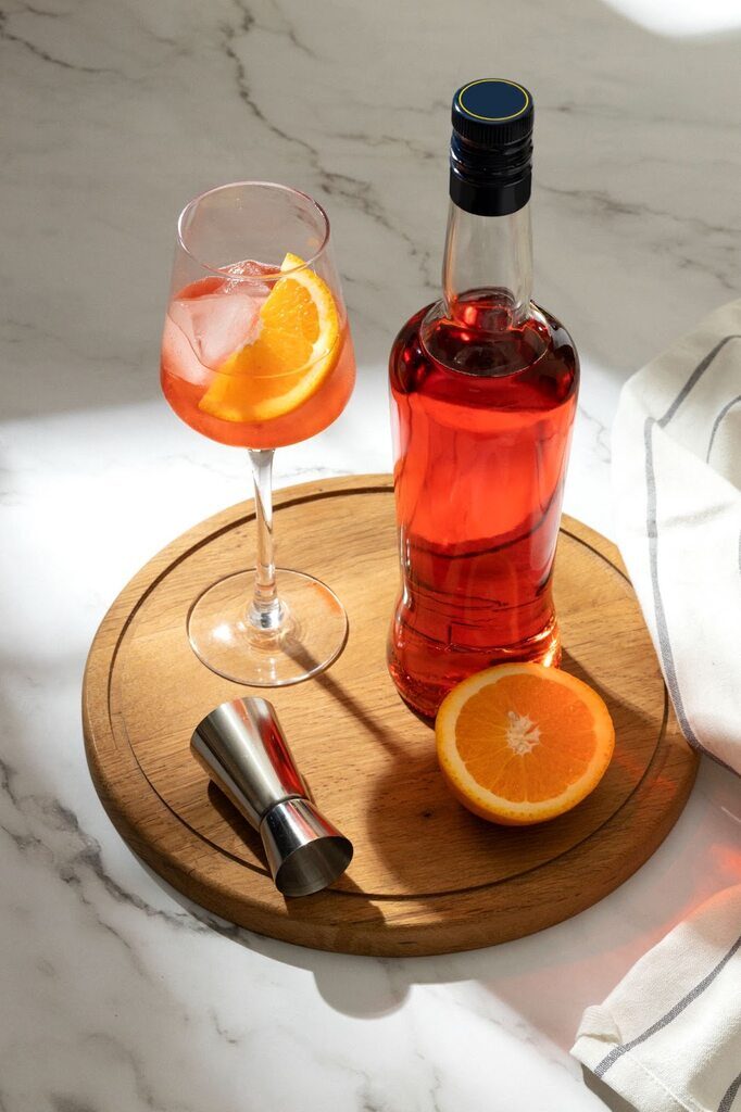 Gin tônica com xarope Monin, servido com laranja em uma tabua de madeira.