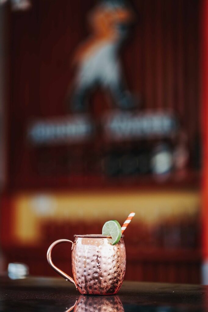 Drink Moscow Mule com gin servido em uma pequena caneca metálica com uma rodela de limão.